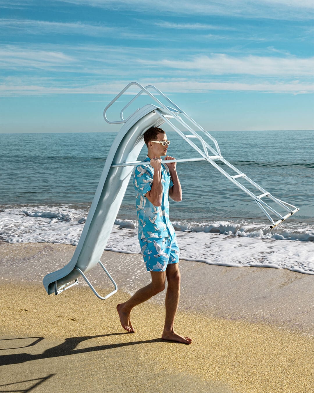 A man walking along the beach carrying a luge